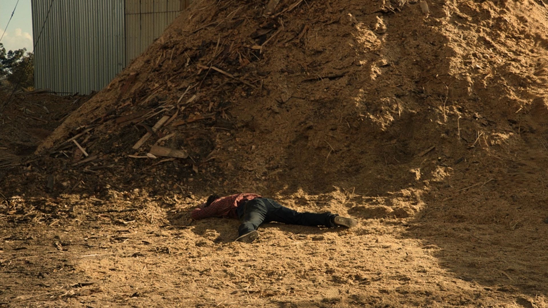 A film still from Liminal County showing a character in a mysterious landscape laying on the ground