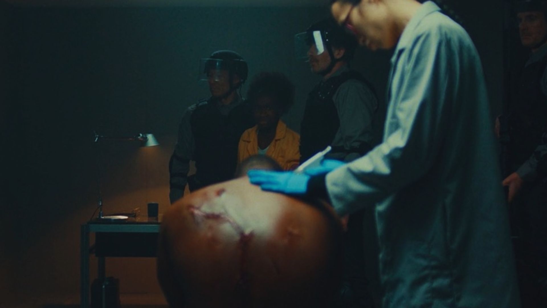 A film still from Of Blood and Dominion showing a character in a medical setting being injected with a substance